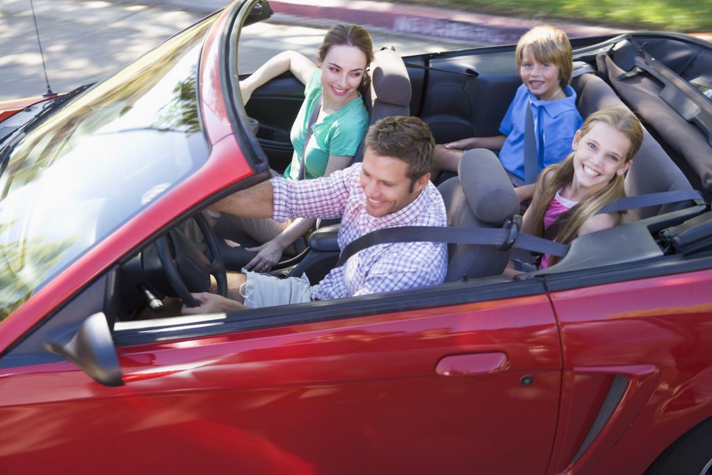 Family in convertible car smiling