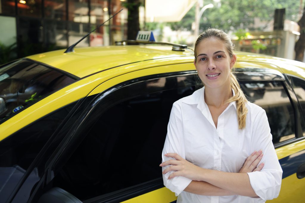 portrait of a proud female taxi driver with her new cab