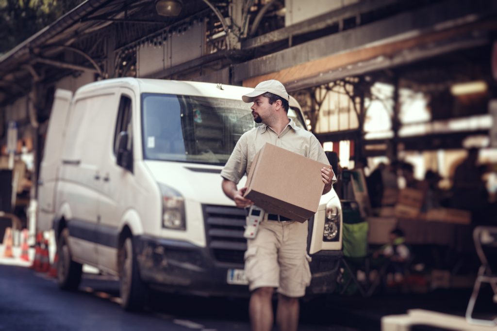 Messenger Delivering Parcel, Walking In Street Next To His Van